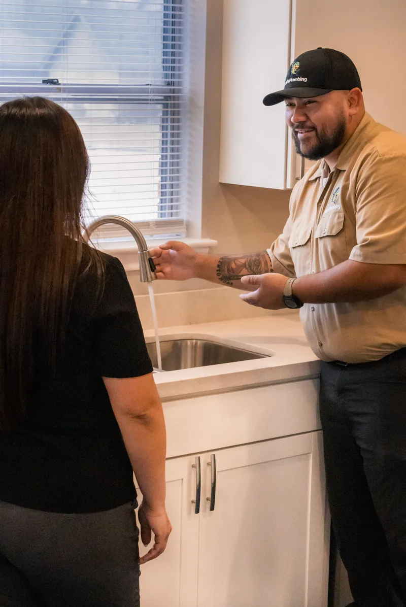 Mahi Plumbing plumber installing a kitchen faucet while the homeowner looks on