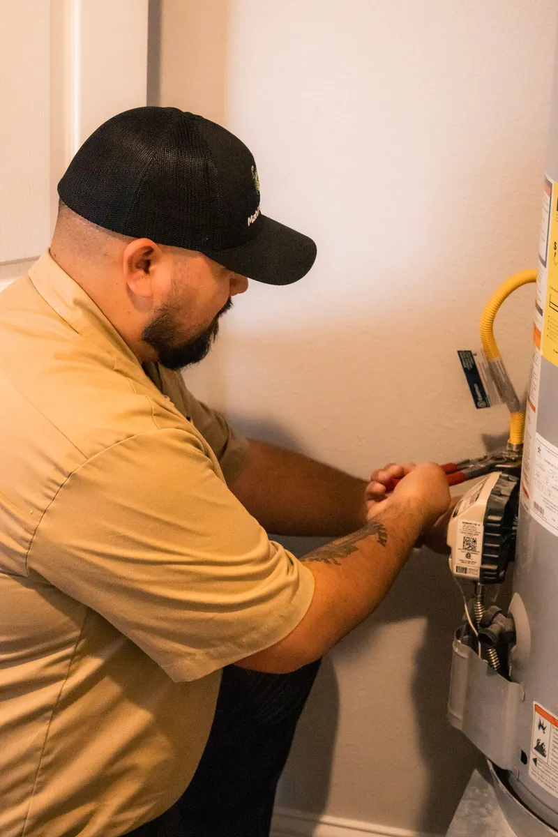 Mahi Plumbing plumber servicing a residential water heater's gas and water connections