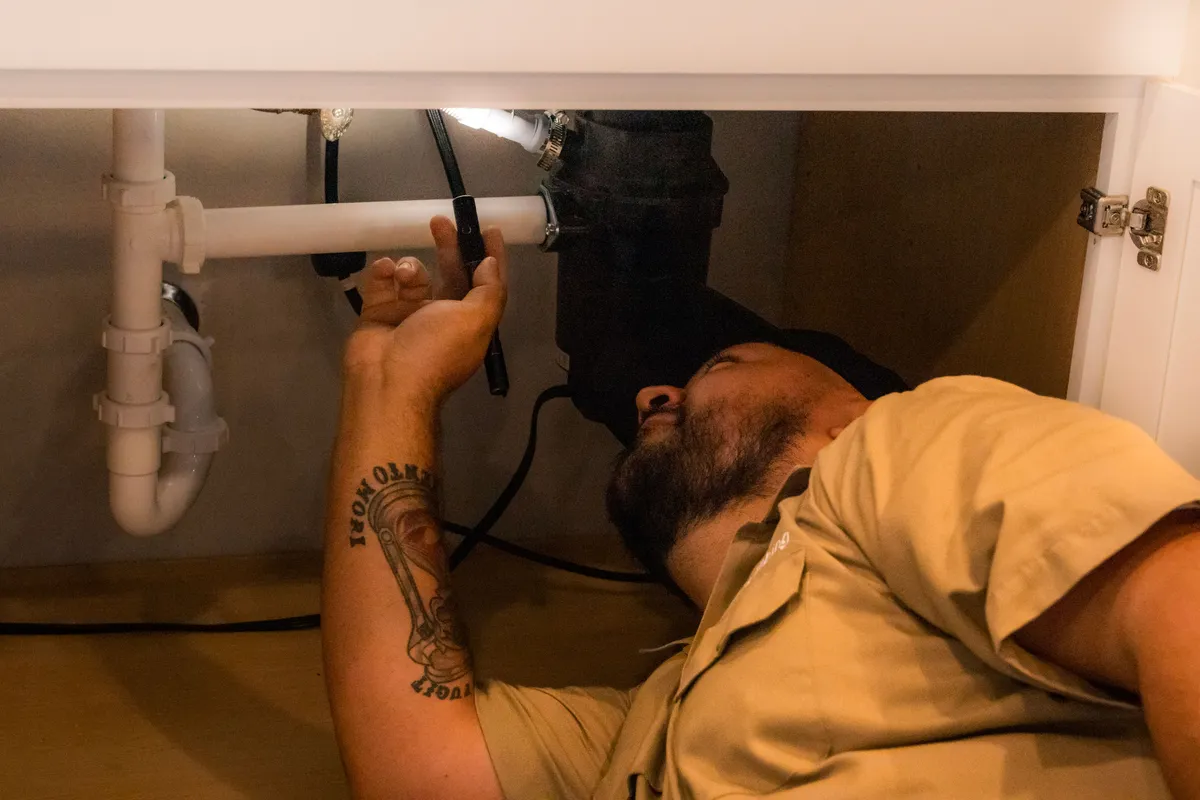 Mahi Plumbing's licensed plumber repairing a P-trap drain line under a sink